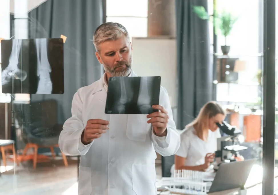 a man in a white coat looking at x-ray